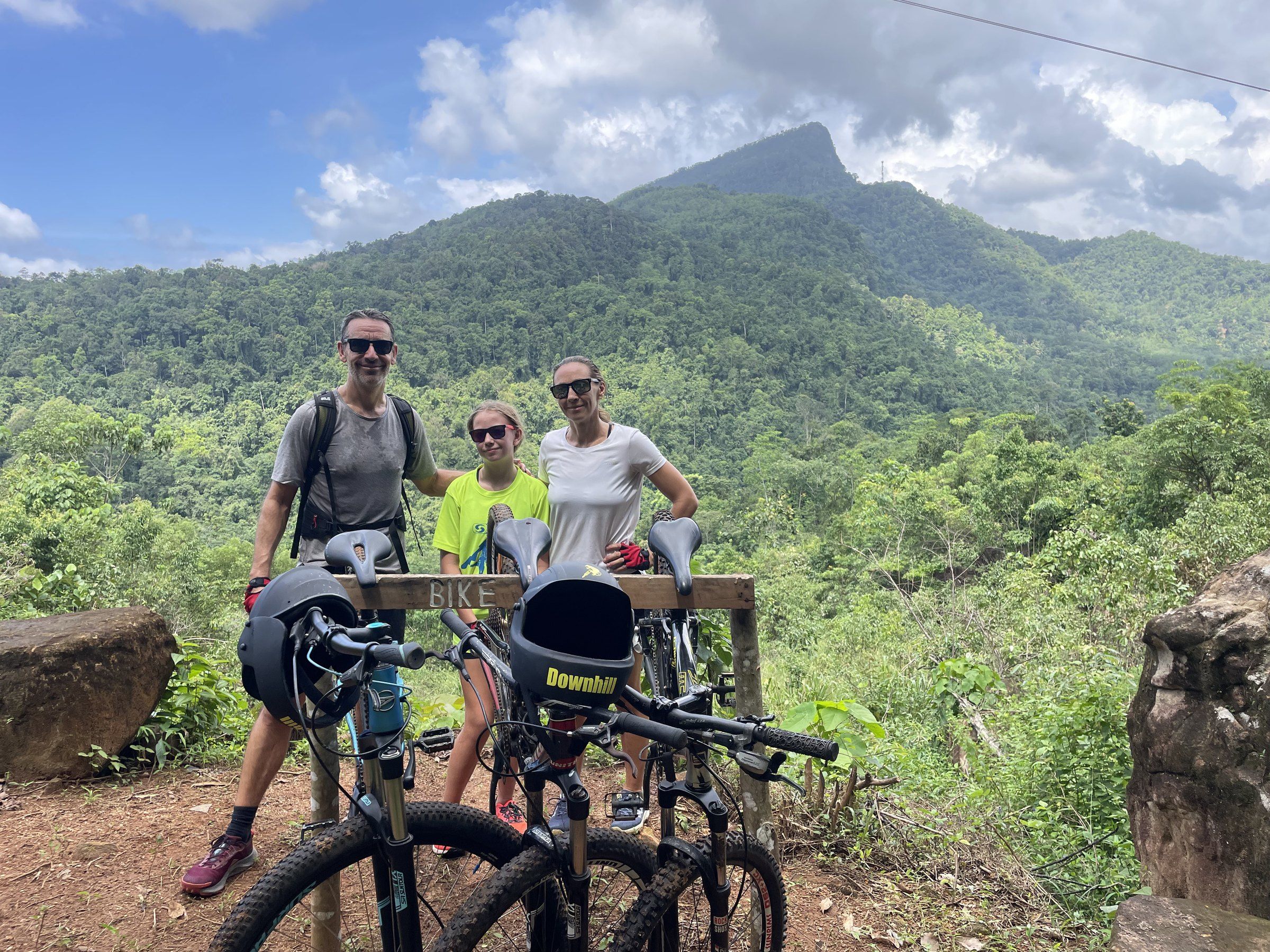 A family of three poses with their bikes at the view point
