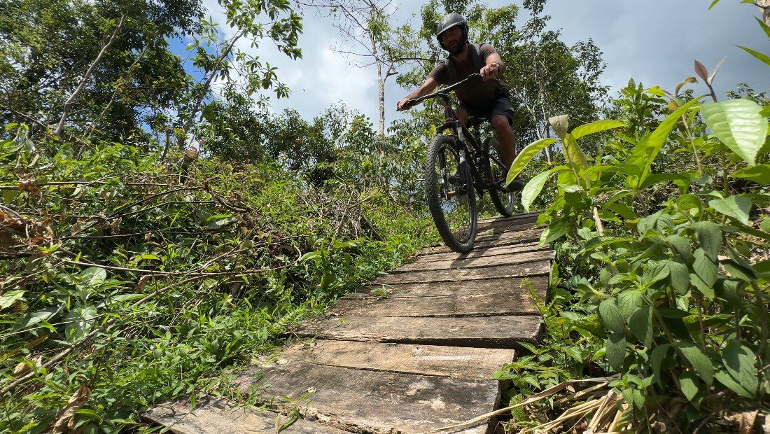A rider rolls onto a plank bridge, seen from low down