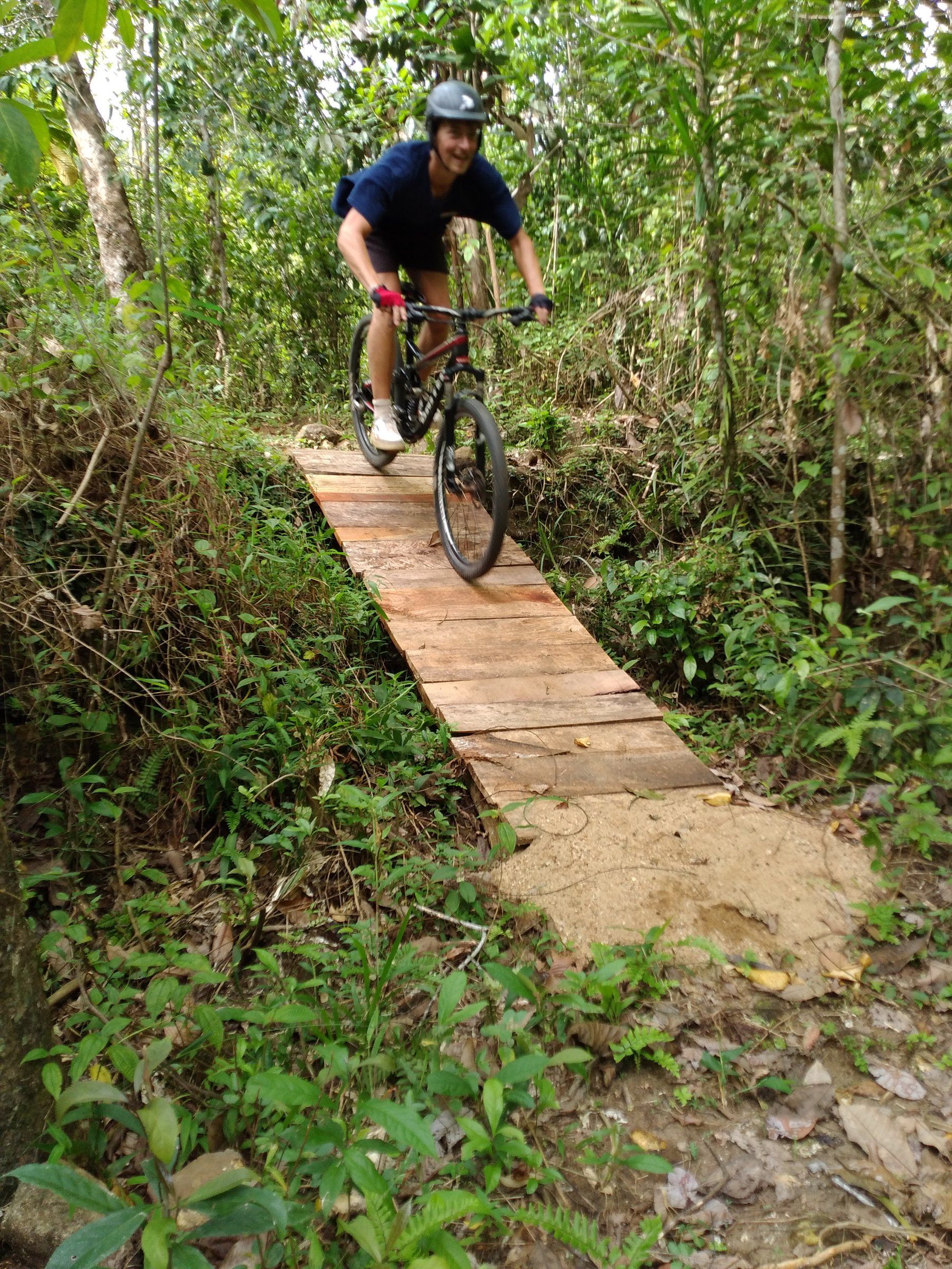 A rider smiles while rolling down a wooden plank bridge in the jungle