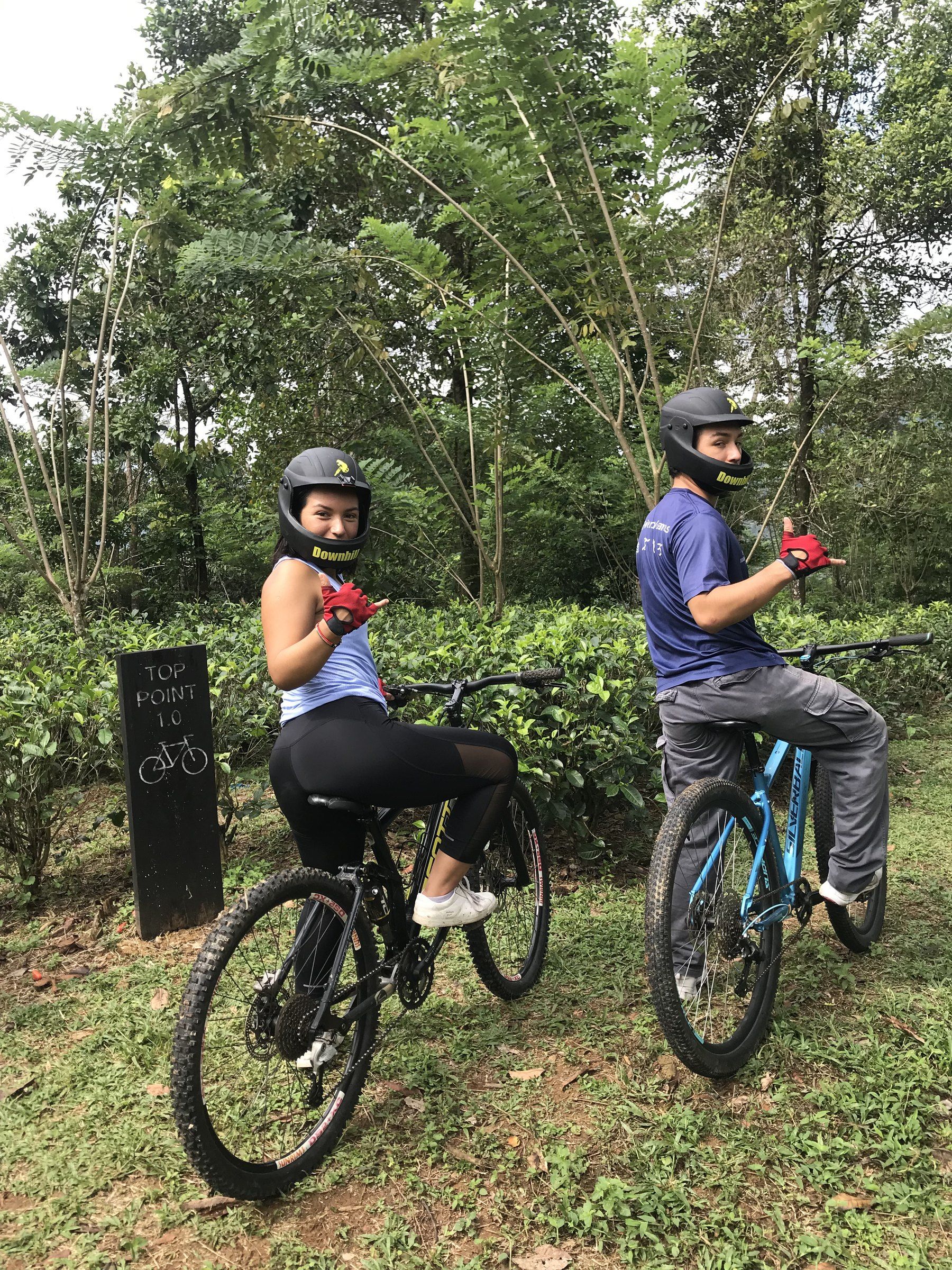 Two riders in full-face helmets wait on their bikes beside the Top Point sign